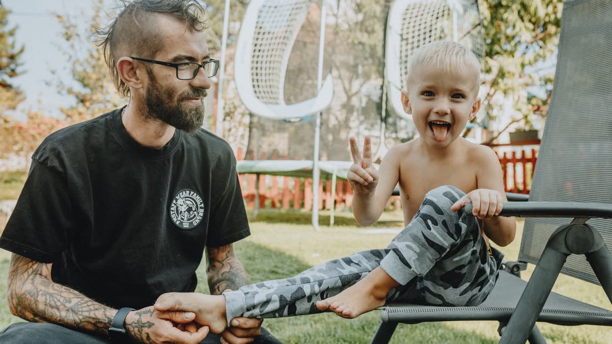 A joyful father and son bonding in a sunny backyard setting. Perfect for family and lifestyle themes.